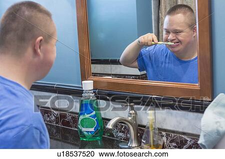 Stock Image - Teen with Down Syndrome brushing his teeth. Fotosearch
