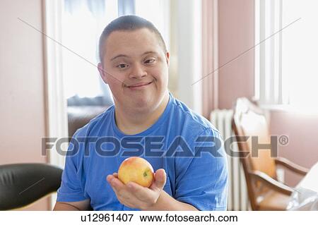 Stock Photo - Teen with Down Syndrome holding fruit. Fotosearch