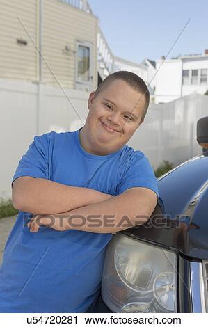 Stock Image - Teen with Down Syndrome leaning against a car. Fotosearch