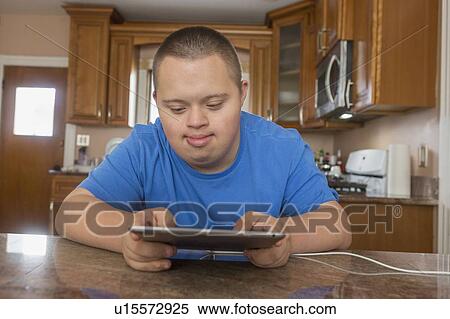 Teen with Down Syndrome using digital tablet View Large Photo Image Stock Photography - Teen with Down Syndrome using digital tablet. Fotosearch