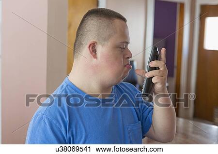 Stock Image - Teen with Down Syndrome using his phone. Fotosearch