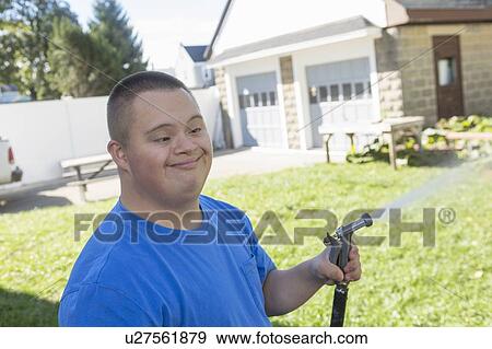 Teen with Down Syndrome watering garden View Large Photo Image Stock Photo - Teen with Down Syndrome watering garden. Fotosearch