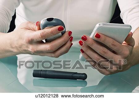 Stock Photo - Using blood glucose meter and smart phone. Fotosearch