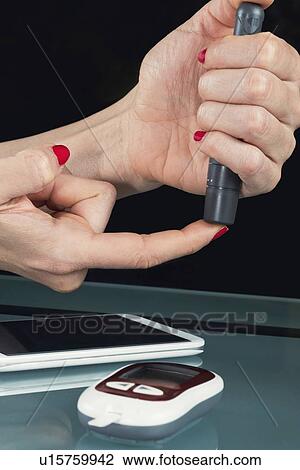Stock Image - Using lancet on finger. Fotosearch