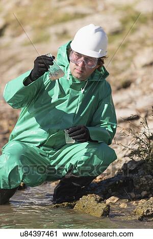 Stock Image - Water quality inspector filling up sample container. Fotosearch