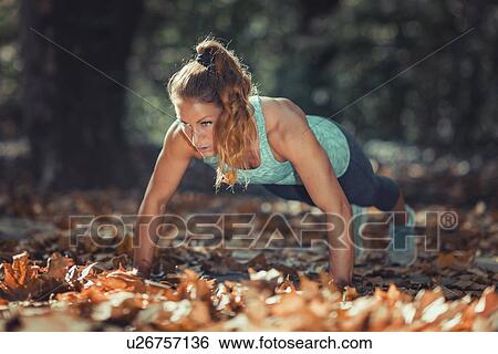 Woman doing push ups in the park View Large Photo Image Stock Photograph - Woman doing push ups in the park. Fotosearch