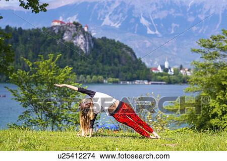 Picture - Woman doing yoga by a lake. Fotosearch
