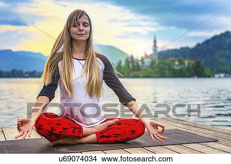 Picture - Woman doing yoga by a lake. Fotosearch
