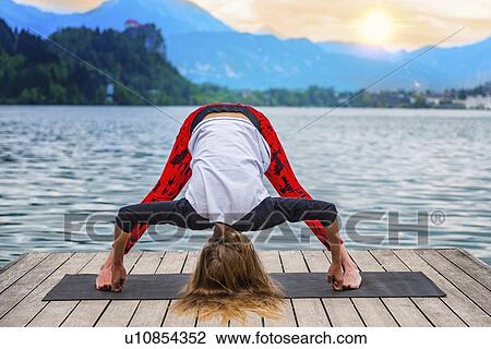 Stock Image - Woman doing yoga by a lake. Fotosearch