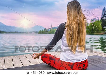 Stock Image - Woman doing yoga by a lake. Fotosearch