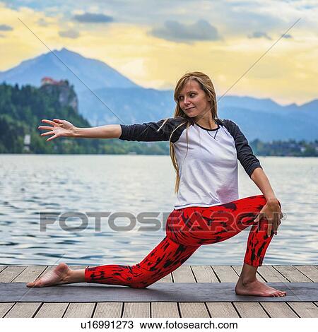 Stock Image - Woman doing yoga by a lake. Fotosearch