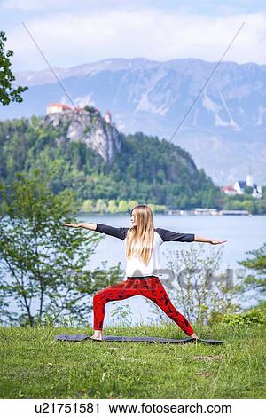 Stock Image - Woman doing yoga by a lake. Fotosearch