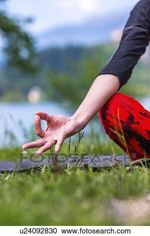Stock Image - Woman doing yoga by a lake. Fotosearch