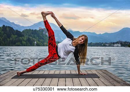 Stock Image - Woman doing yoga by a lake. Fotosearch