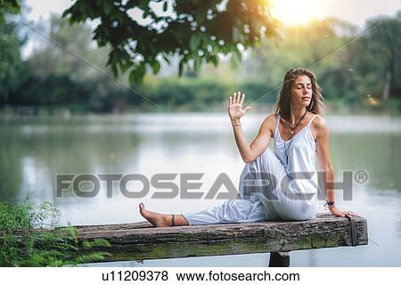 Stock Photo - Woman doing yoga by a lake. Fotosearch