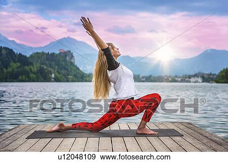 Stock Photo - Woman doing yoga by a lake. Fotosearch