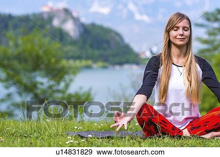 Stock Photo - Woman doing yoga by a lake. Fotosearch