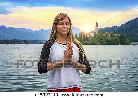 Stock Photo - Woman doing yoga by a lake. Fotosearch
