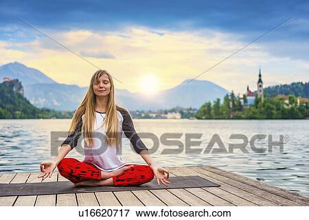 Stock Photo - Woman doing yoga by a lake. Fotosearch