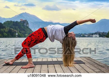 Stock Photo - Woman doing yoga by a lake. Fotosearch