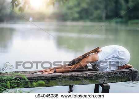 Stock Photo - Woman doing yoga by a lake. Fotosearch