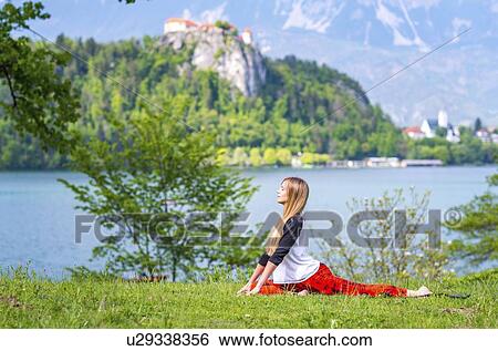 Stock Photograph - Woman doing yoga by a lake. Fotosearch