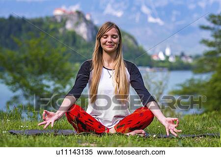 Stock Photography - Woman doing yoga by a lake. Fotosearch