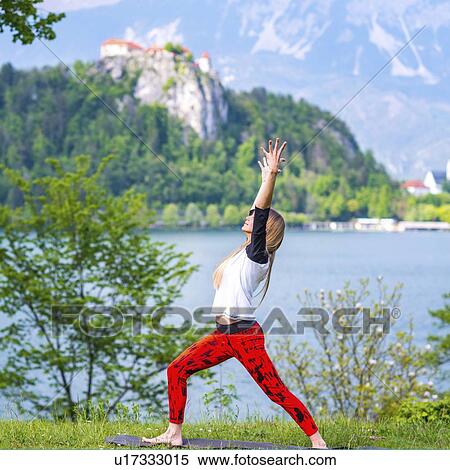 Stock Photography - Woman doing yoga by a lake. Fotosearch