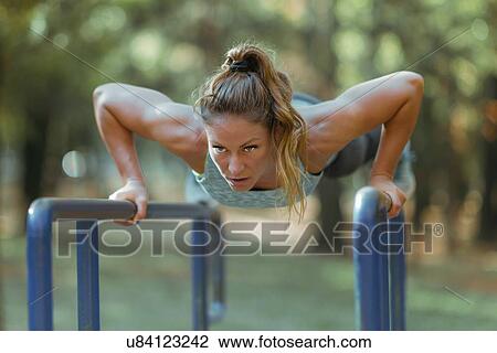 Woman exercising on parallel bars outdoors View Large Photo Image Stock Image - Woman exercising on parallel bars outdoors. Fotosearch