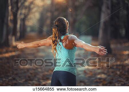 Stock Photography - Woman exercising outdoors, standing with raised arms. Fotosearch