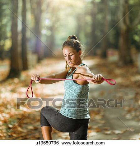 Stock Photograph - Woman exercising with elastic band outdoors. Fotosearch