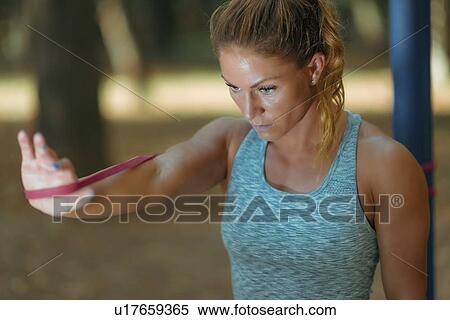 Stock Photography - Woman exercising with elastic band outdoors. Fotosearch