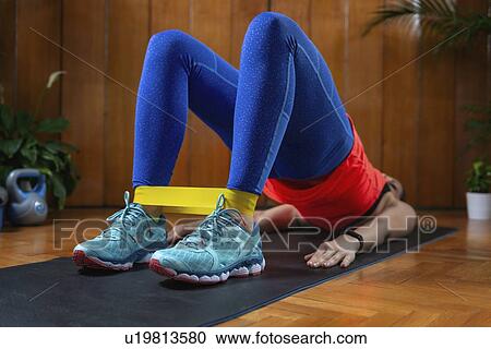 Stock Image - Woman exercising with resistance band. Fotosearch