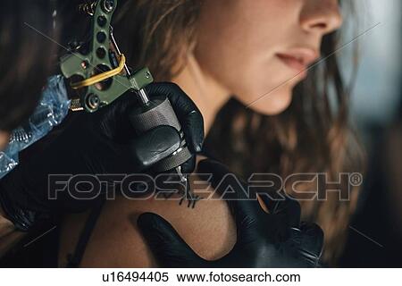 Stock Photography - Woman getting a shoulder tattoo. Fotosearch