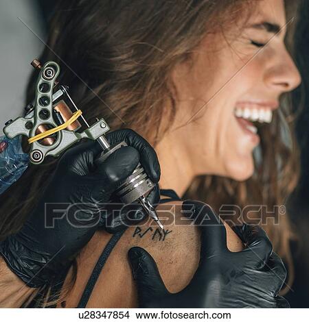 Picture - Woman getting a tattoo. Fotosearch