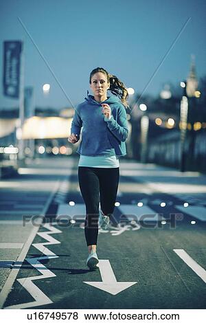 Stock Photo - Woman jogging in city at night. Fotosearch
