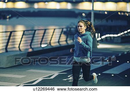 Stock Photograph - Woman jogging in city at night. Fotosearch