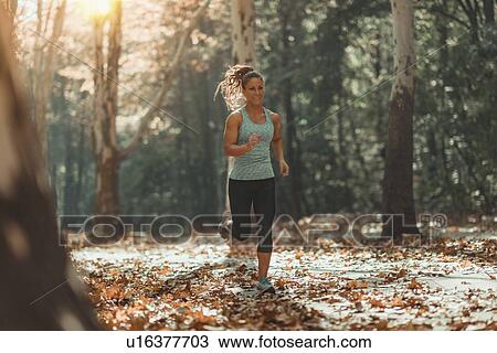 Stock Image - Woman jogging outdoors in autumn. Fotosearch