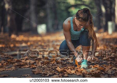 Stock Image - Woman kneeling and tying shoe. Fotosearch