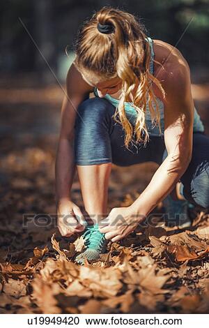 Stock Image - Woman kneeling and tying shoe. Fotosearch