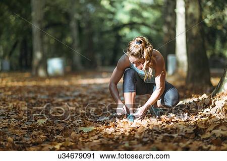 Stock Image - Woman kneeling and tying shoe. Fotosearch