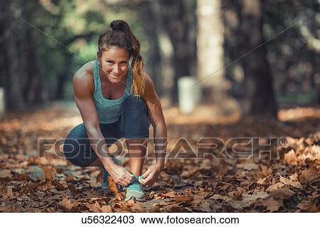 Stock Image - Woman kneeling and tying shoe. Fotosearch