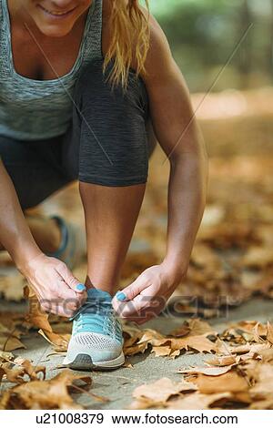 Stock Photo - Woman kneeling and tying shoe. Fotosearch