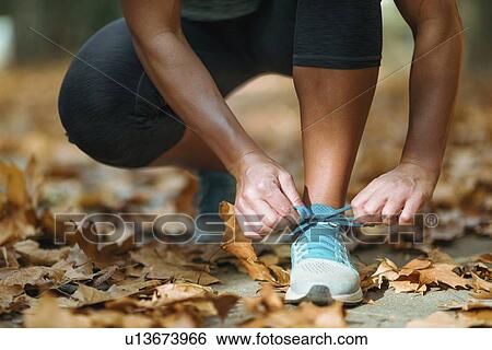 Stock Photograph - Woman kneeling and tying shoe. Fotosearch