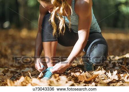 Woman kneeling and tying shoe View Large Photo Image Stock Photograph - Woman kneeling and tying shoe. Fotosearch