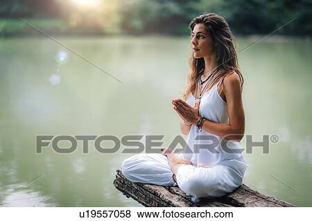 Woman meditating by a lake View Large Photo Image Stock Photo - Woman meditating by a lake. Fotosearch