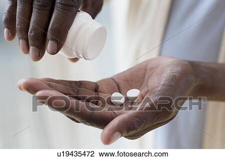 Stock Image - Woman pouring pills. Fotosearch