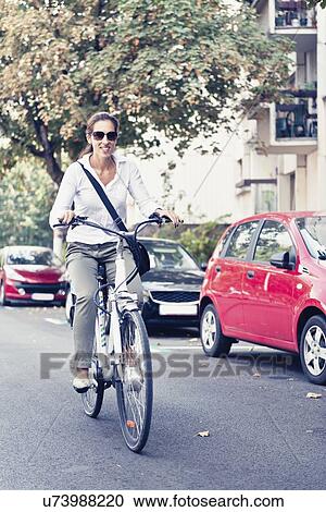 Woman riding electric bicycle View Large Photo Image Stock Image - Woman riding electric bicycle. Fotosearch