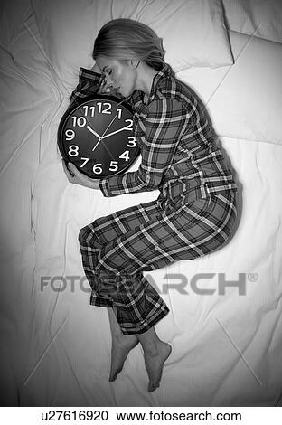 Stock Image - Woman sleeping in bed with clock. Fotosearch
