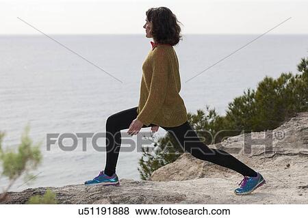 Stock Photo - Woman stretching next to the sea. Fotosearch